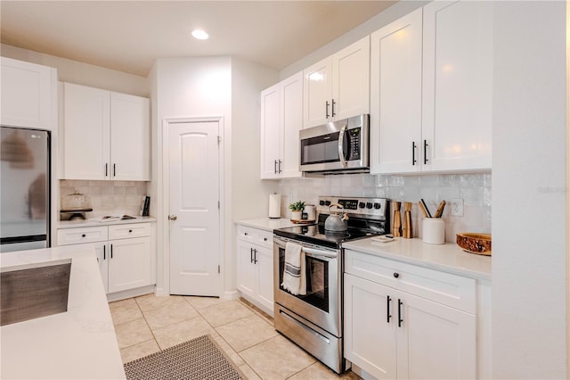 kitchen featuring light tile patterned floors, stainless steel appliances, light countertops, decorative backsplash, and white cabinets