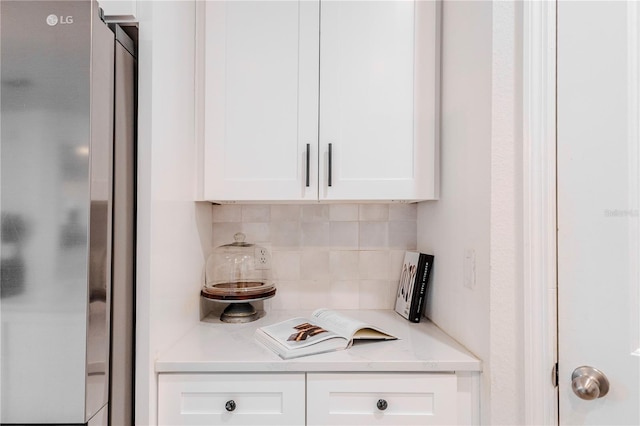 kitchen featuring freestanding refrigerator, white cabinets, and backsplash