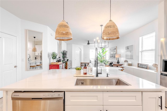 kitchen with arched walkways, a sink, white cabinetry, open floor plan, and stainless steel dishwasher