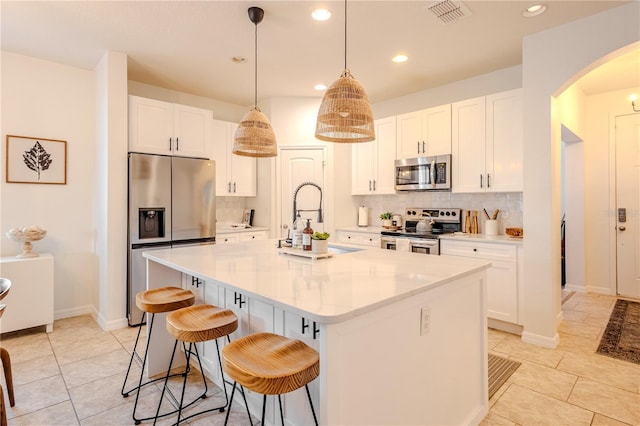 kitchen with arched walkways, a sink, visible vents, light countertops, and appliances with stainless steel finishes