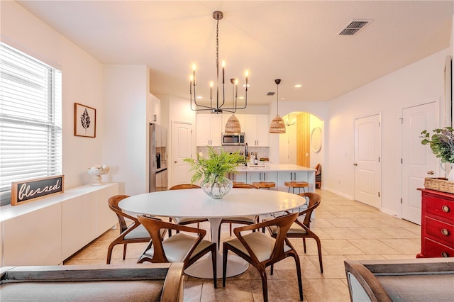 dining room with arched walkways, light tile patterned floors, visible vents, and baseboards