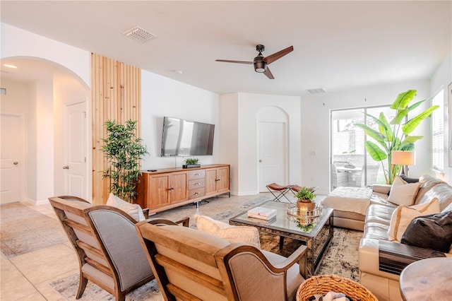 living area with arched walkways, ceiling fan, light tile patterned floors, and visible vents