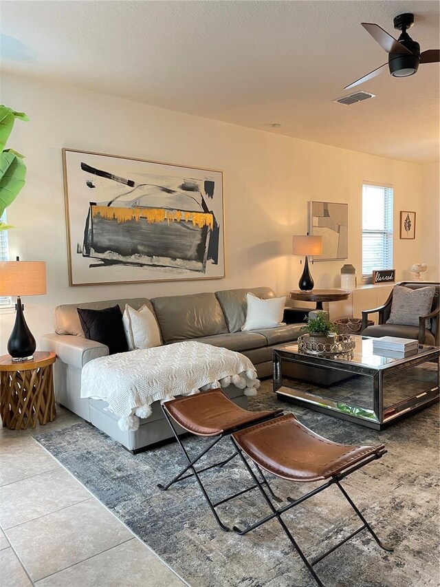 tiled living room featuring a textured ceiling, visible vents, and a ceiling fan