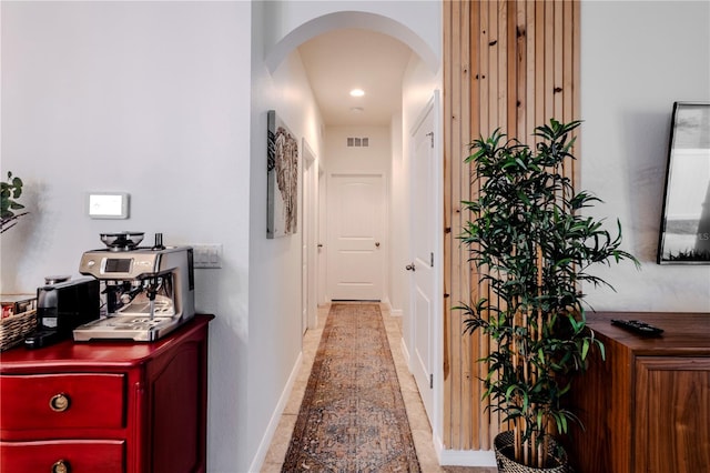 corridor with arched walkways, visible vents, and baseboards