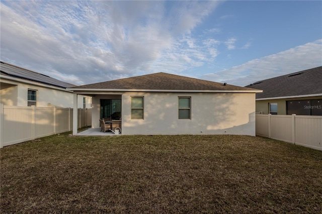 rear view of property featuring a yard, a patio area, a fenced backyard, and stucco siding