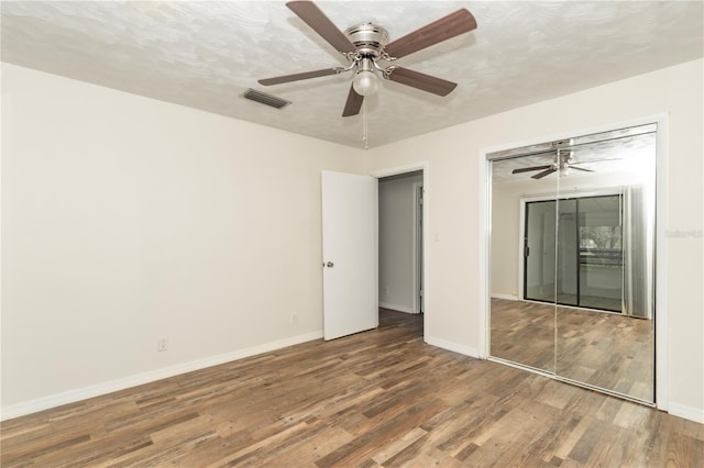 unfurnished bedroom with a closet, ceiling fan, hardwood / wood-style floors, and a textured ceiling