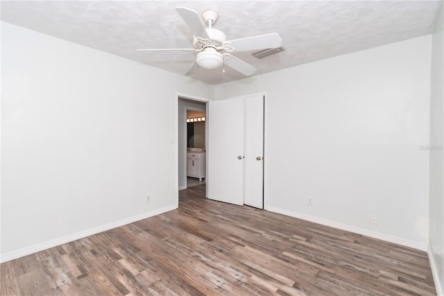 spare room with ceiling fan, a textured ceiling, and wood-type flooring