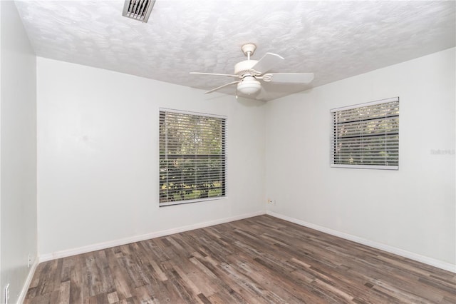 empty room with ceiling fan, a textured ceiling, and dark hardwood / wood-style flooring