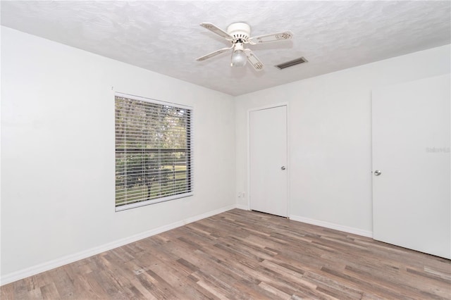 spare room featuring ceiling fan, wood-type flooring, and a textured ceiling