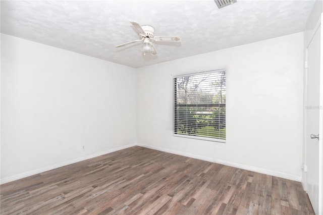 spare room featuring dark wood-type flooring, a textured ceiling, and ceiling fan