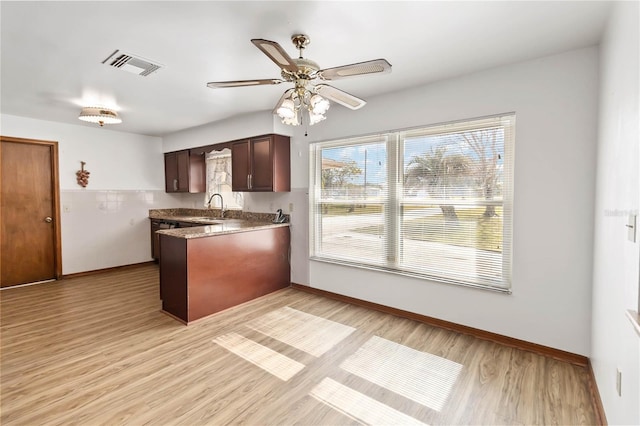 kitchen with kitchen peninsula, ceiling fan, sink, light hardwood / wood-style floors, and dark brown cabinetry