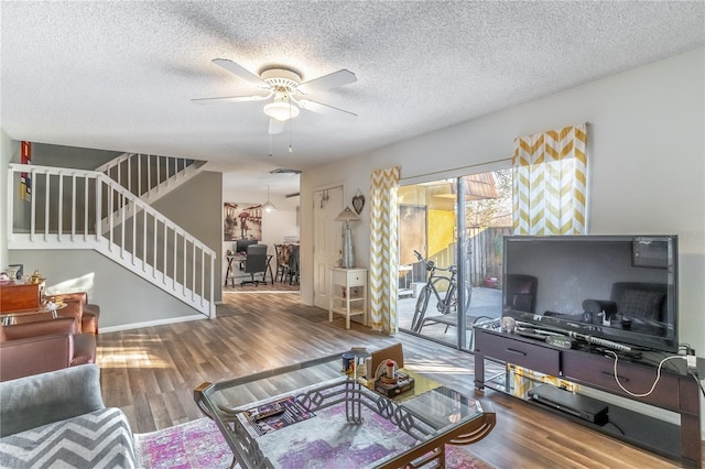 living room with a textured ceiling, wood-type flooring, and ceiling fan