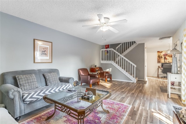 living room featuring hardwood / wood-style flooring, ceiling fan, and a textured ceiling