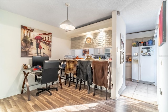 home office featuring light hardwood / wood-style floors and a textured ceiling