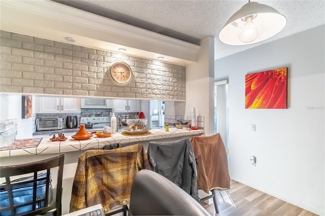 kitchen featuring stove, white cabinetry, tile countertops, and a kitchen bar