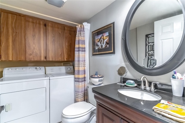 bathroom featuring washing machine and clothes dryer, vanity, and toilet