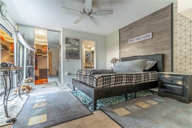 carpeted bedroom featuring ceiling fan, a textured ceiling, a walk in closet, a closet, and wood walls