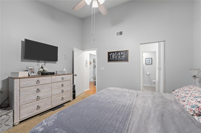 carpeted bedroom featuring connected bathroom, a high ceiling, and ceiling fan