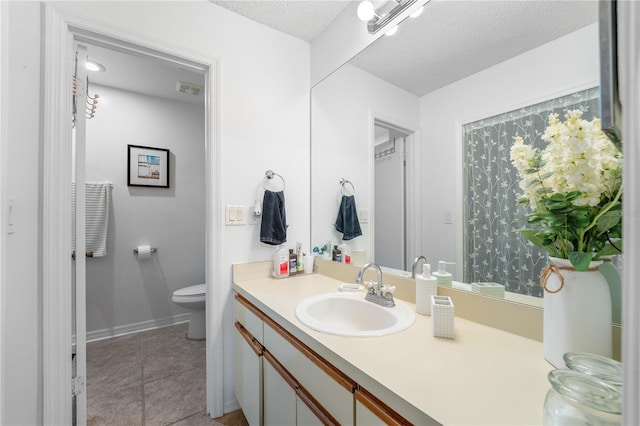 bathroom featuring vanity, toilet, tile patterned floors, and a textured ceiling