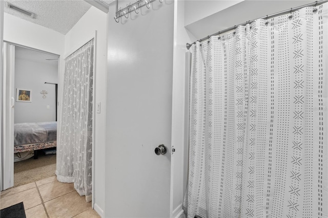 bathroom with a textured ceiling, tile patterned floors, and a shower with curtain