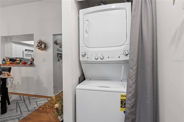 laundry area with wood-type flooring and stacked washing maching and dryer