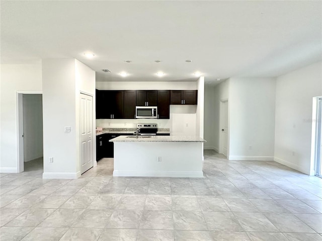 kitchen featuring a kitchen island with sink, light stone countertops, stainless steel appliances, and sink