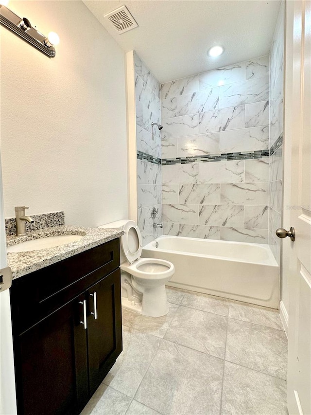 full bathroom featuring tiled shower / bath, vanity, and toilet