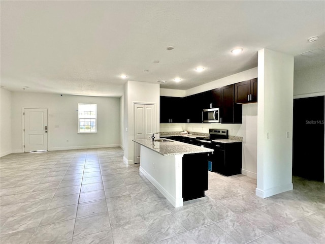 kitchen featuring an island with sink, light stone countertops, sink, and electric range