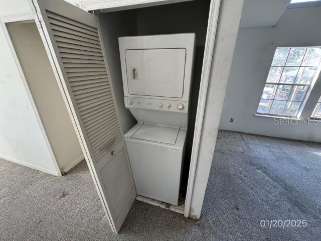 laundry area featuring carpet flooring and stacked washer and dryer