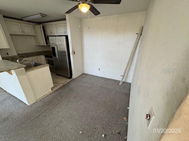 kitchen with stainless steel fridge with ice dispenser, white cabinetry, light colored carpet, and sink