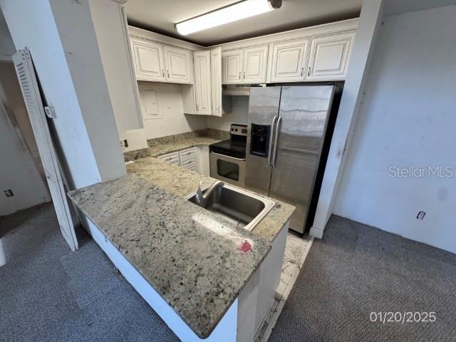 kitchen with sink, white cabinetry, appliances with stainless steel finishes, and kitchen peninsula