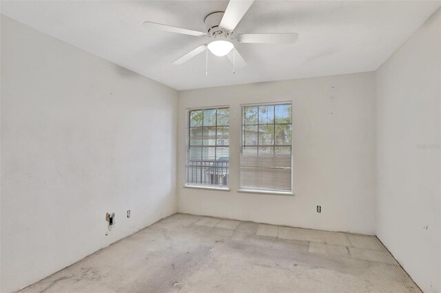 empty room featuring a ceiling fan and light colored carpet