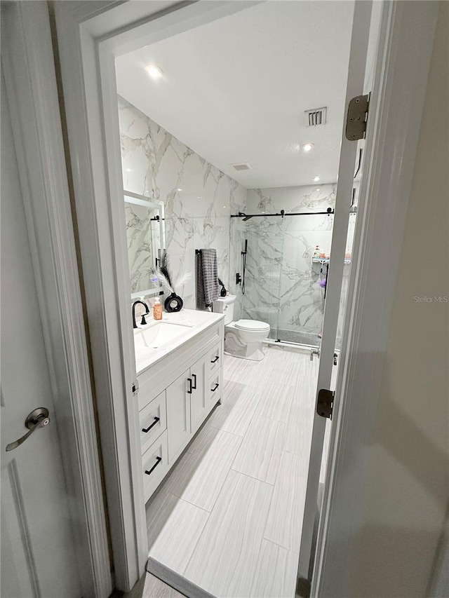 bathroom with a shower with door, toilet, and vanity