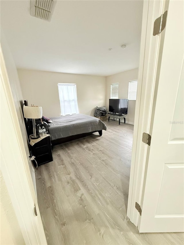 bedroom with hardwood / wood-style flooring and multiple windows