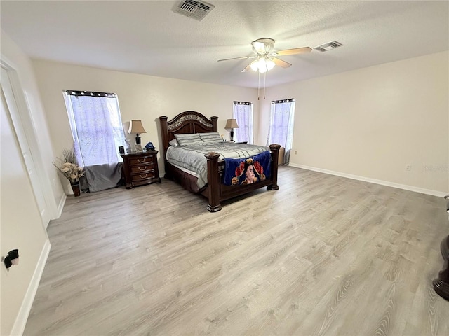 bedroom with ceiling fan, light hardwood / wood-style floors, and a textured ceiling