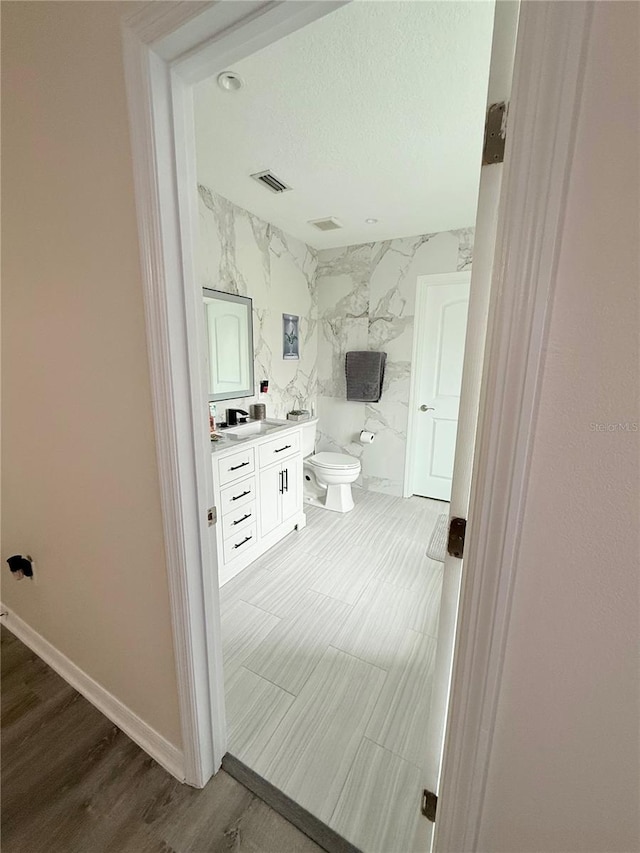 bathroom with vanity, toilet, and hardwood / wood-style floors