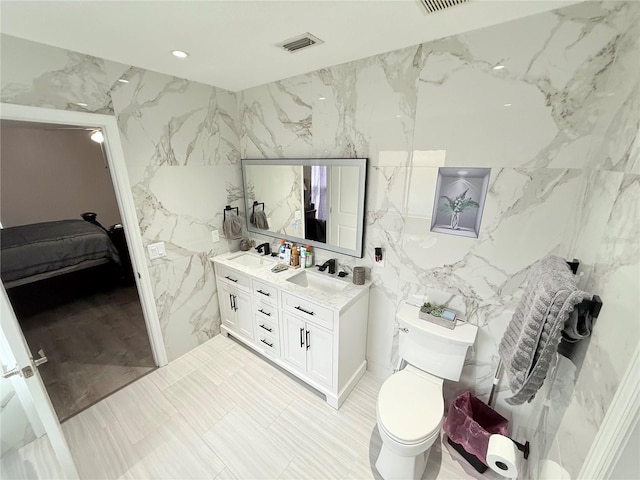 bathroom featuring vanity, toilet, and tile walls