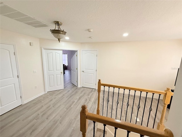 corridor with a textured ceiling and light wood-type flooring