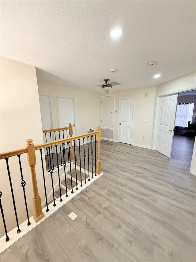 corridor featuring a textured ceiling and light hardwood / wood-style flooring