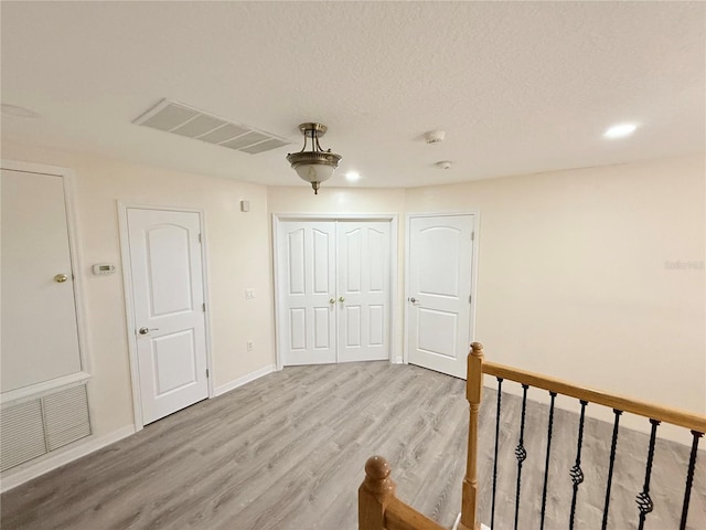 interior space with ceiling fan, light hardwood / wood-style floors, and a textured ceiling