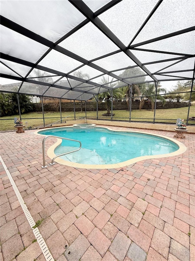 view of swimming pool with glass enclosure, a patio area, an in ground hot tub, and a lawn