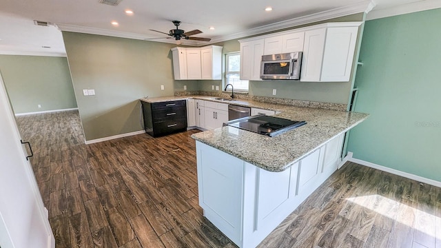 kitchen featuring appliances with stainless steel finishes, white cabinetry, sink, kitchen peninsula, and dark hardwood / wood-style flooring