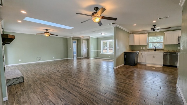 kitchen with a skylight, white cabinetry, stainless steel dishwasher, sink, and ornamental molding