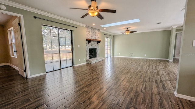 unfurnished living room with a skylight, a stone fireplace, ornamental molding, and plenty of natural light