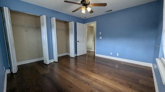 unfurnished bedroom featuring ceiling fan, dark hardwood / wood-style flooring, and two closets