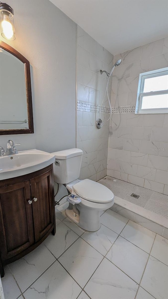 bathroom featuring vanity, toilet, and a tile shower