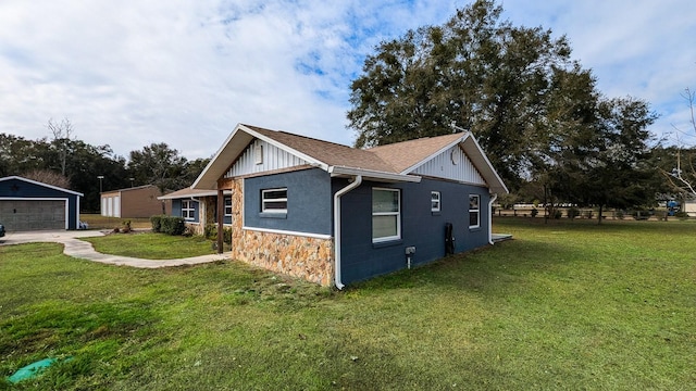 view of side of property featuring a garage, a lawn, and an outbuilding