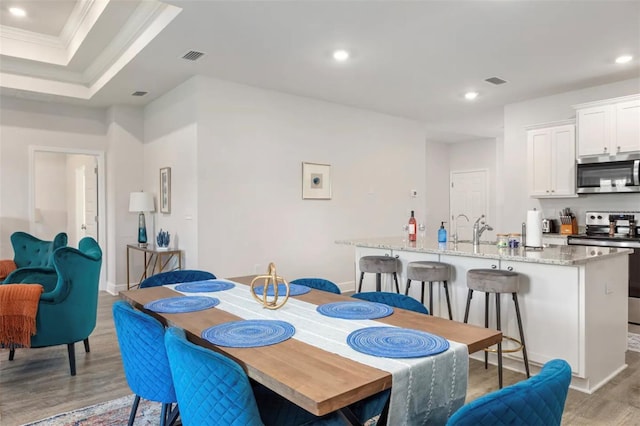 dining area featuring hardwood / wood-style flooring, sink, and crown molding