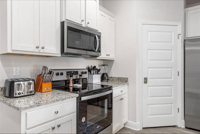 kitchen featuring light stone counters, white cabinetry, and stainless steel appliances