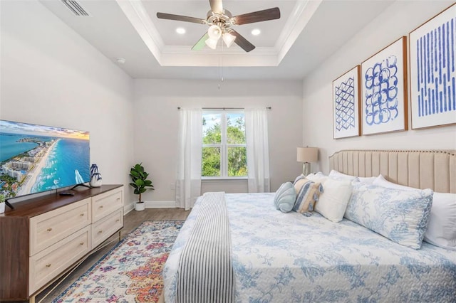 bedroom featuring wood-type flooring, ceiling fan, and a raised ceiling